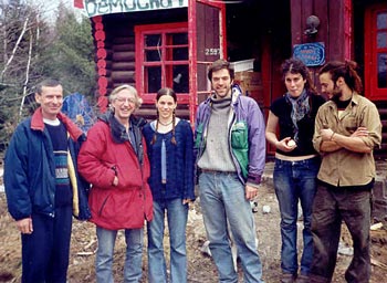 Richard Desjardins en visite à Guindonville, avril 2003, avec des résidents, devant la maison de bois rond.